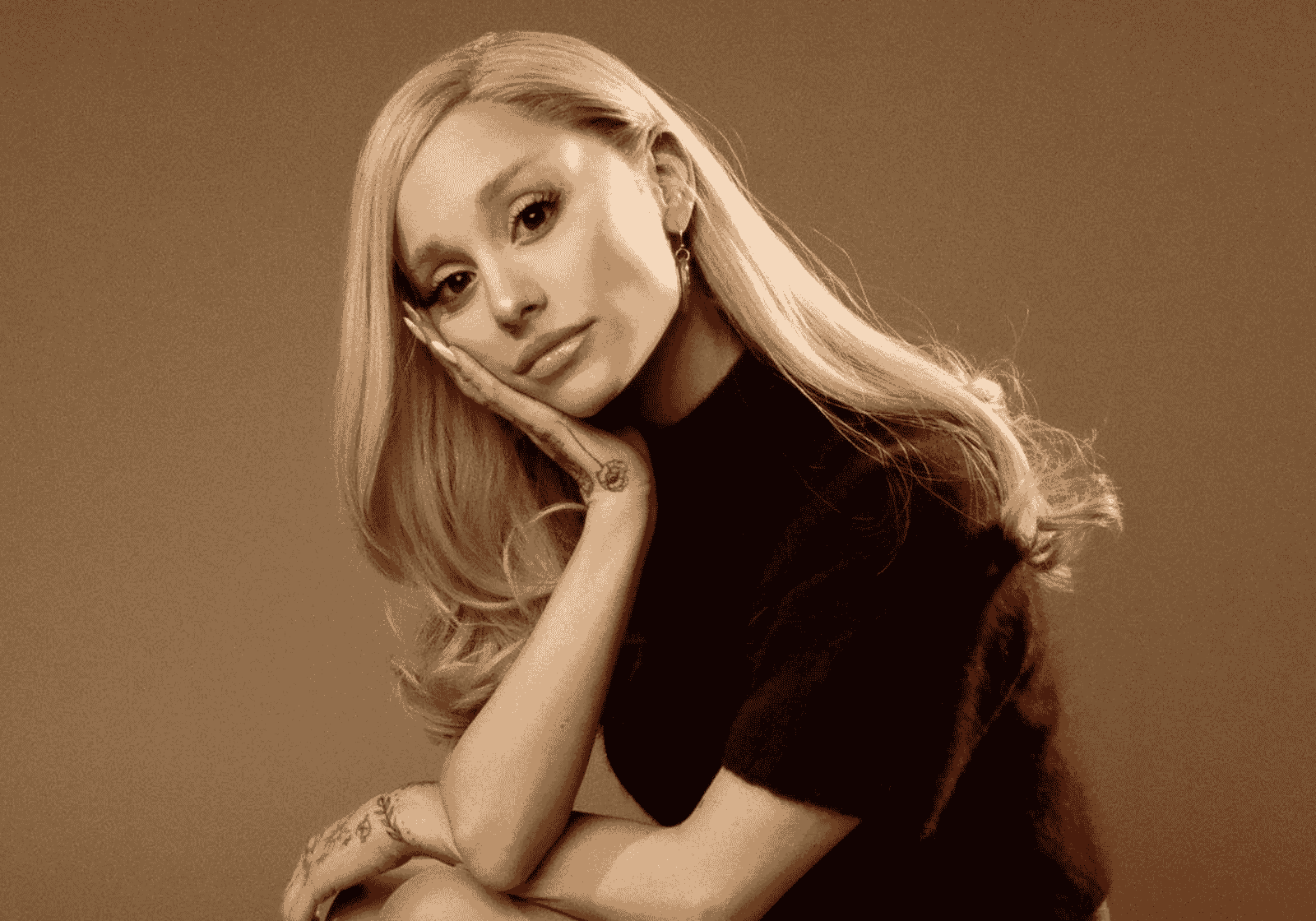 Ariana Grande szépia tónusú portréja, arcát a kezére támasztva