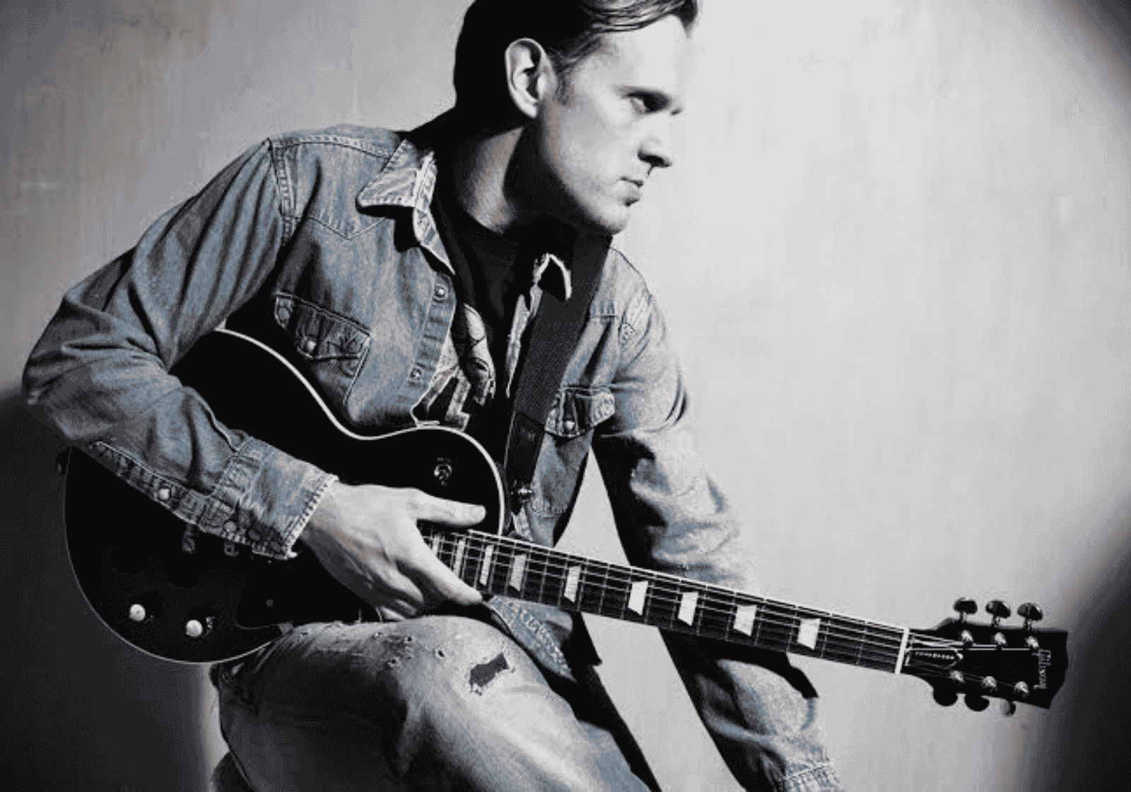 A fiatal Joe Bonamassa fekete-fehér portrén, gitárral