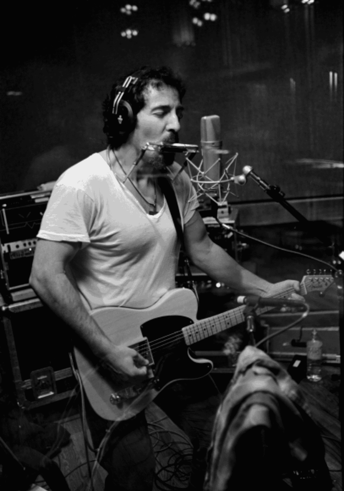 Bruce Springsteen fekete-fehér stúdiófelvételen, gitárral és szájharmonikával