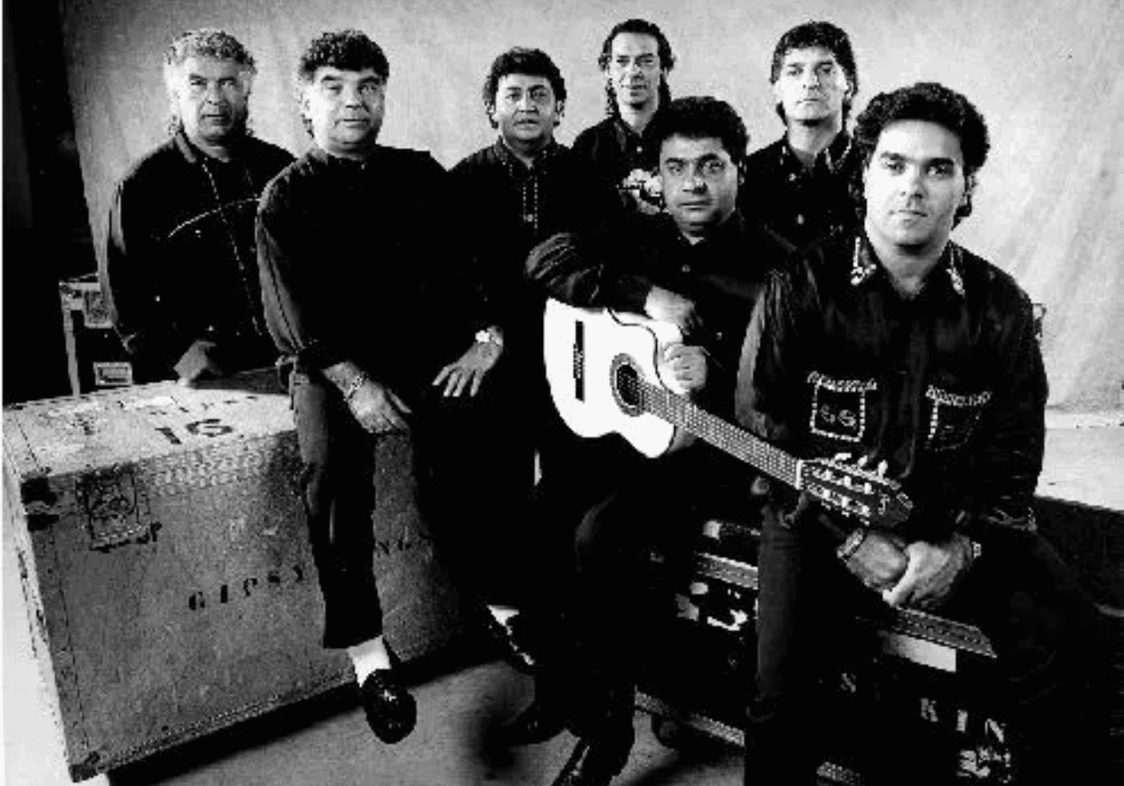 A Gipsy Kings tagjai fekete-fehér stúdiófotón, gitárokkal és hangtechnikai ládával