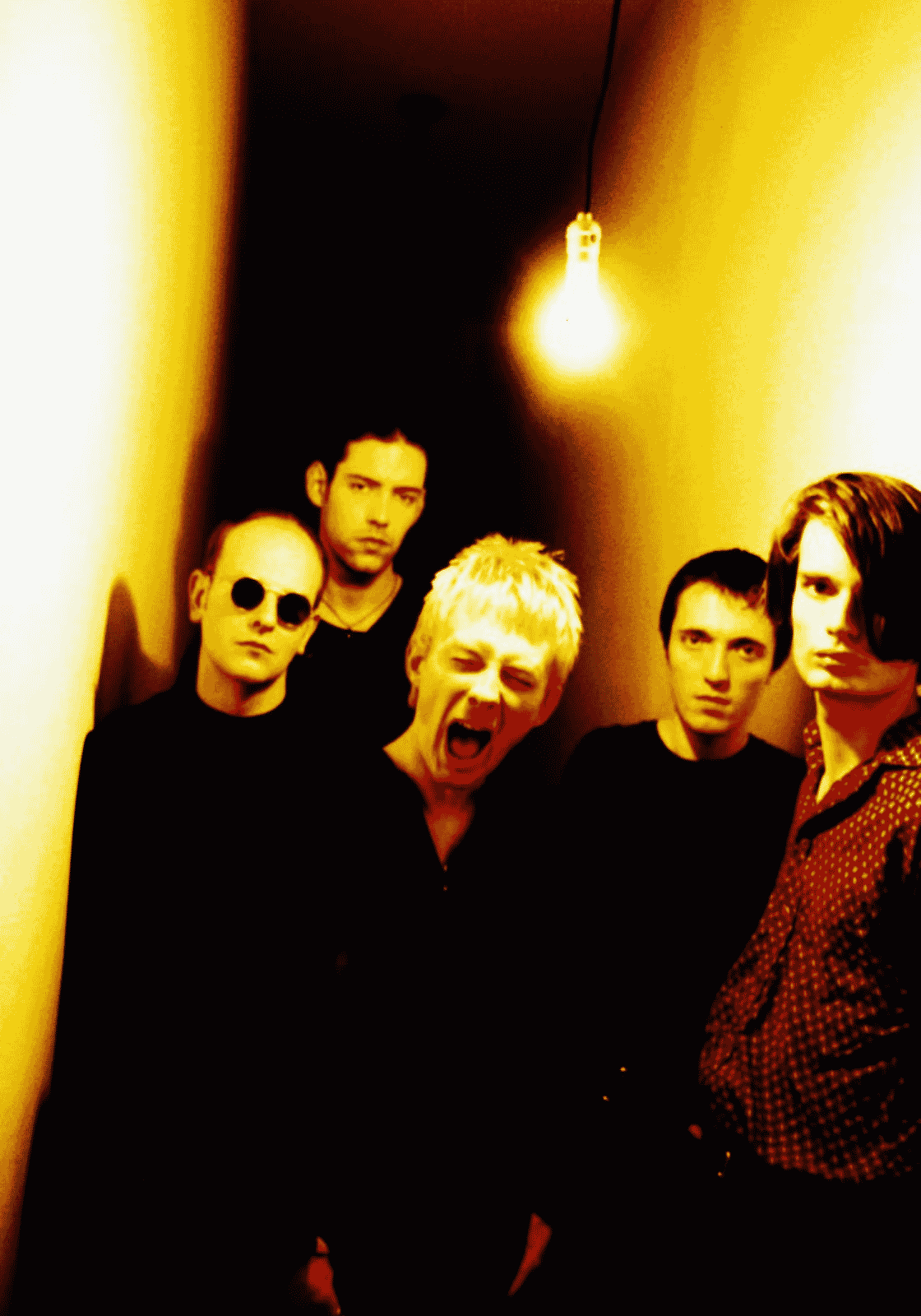 A Radiohead öt tagja erős sárga fényben, Thom Yorke középen